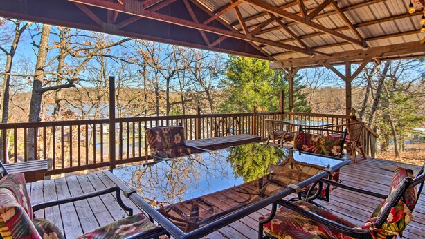 A covered outdoor deck with wooden furniture and a glass table. - Waterfront House w/ Boat Slip on Lake Eufaula! (Canadian)