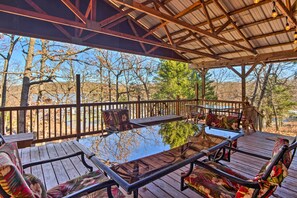 A covered outdoor deck with wooden furniture and a glass table. - Waterfront House w/ Boat Slip on Lake Eufaula! (Canadian)