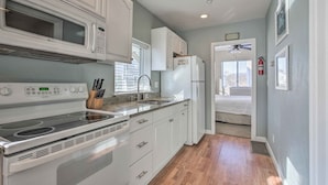 A kitchen with white cabinets, a microwave, a stove, and a refrigerator. - York Beachfront Condo - Steps to Long Sands! (York Beach)