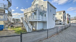 A two-story building with a balcony on the second floor, a staircase leading to the upper level, and a fenced yard. - York Beachfront Condo - Steps to Long Sands! (York Beach)