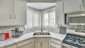 A kitchen with white cabinets, a stainless steel stove, a microwave, and a coffee maker.