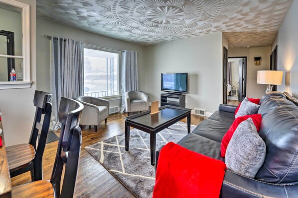 A modern living room with a sofa, chairs, a coffee table, and a television.