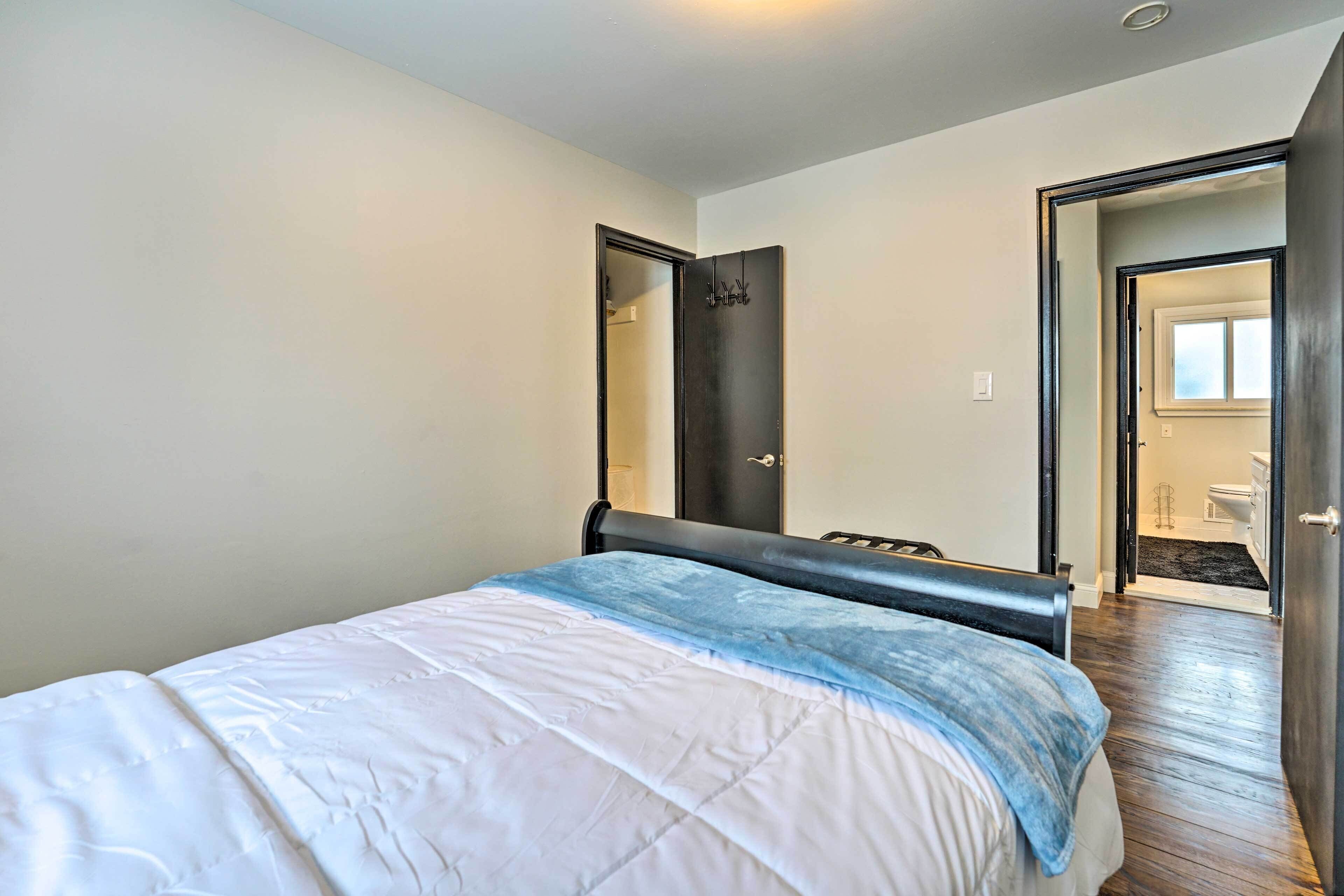 Een slaapkamer met een bed, een deur en uitzicht op een badkamer.