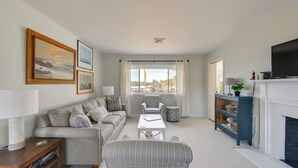 Ein Wohnzimmer mit Sofa, Sessel, Couchtisch und Kamin.