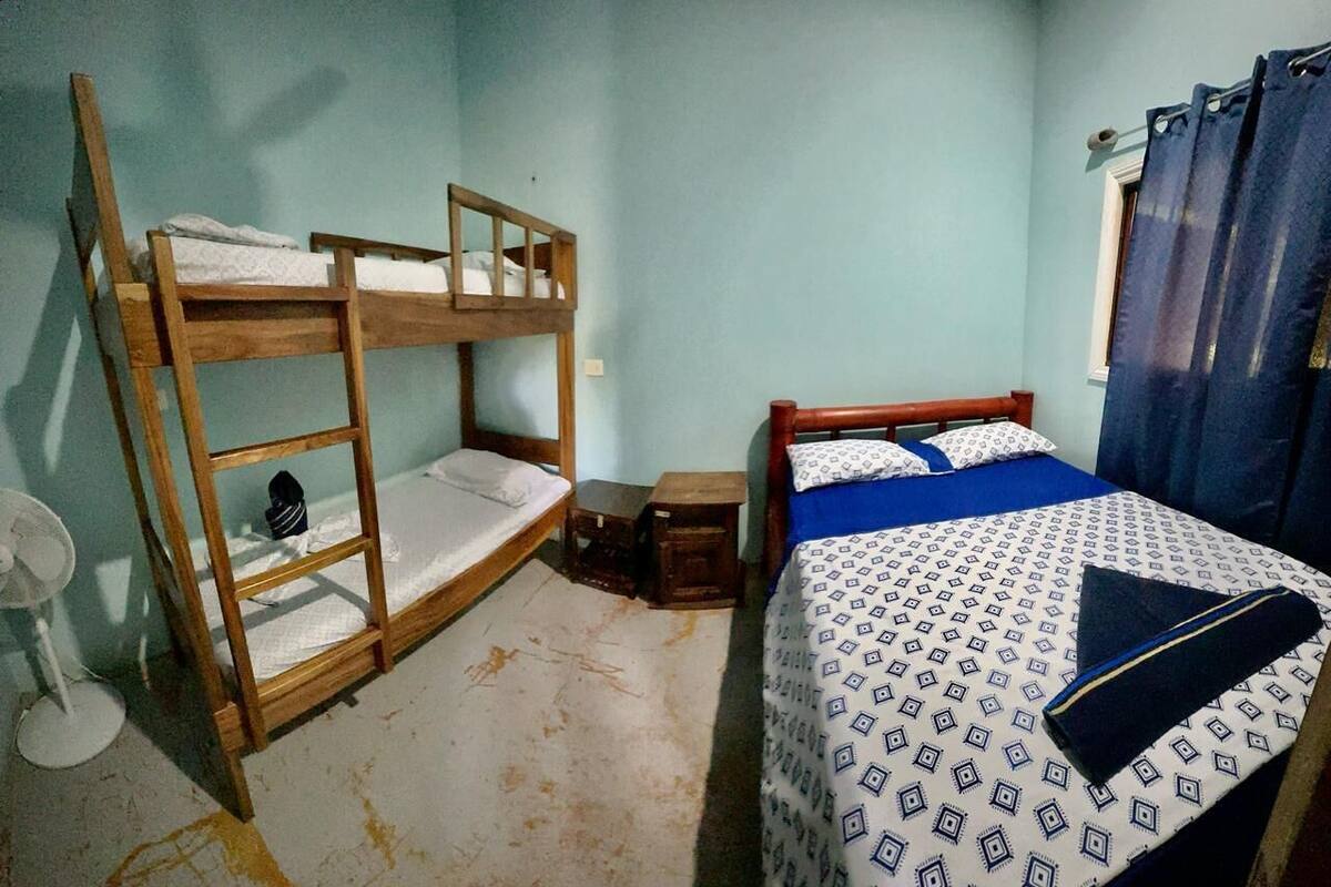 Une chambre avec des lits superposés, une petite table et un ventilateur.