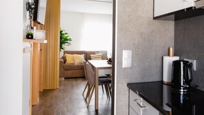 Eine moderne Küche mit schwarzem Arbeitsplatz, einer Kaffeemaschine und einem Essbereich mit Holztisch und Stühlen.
