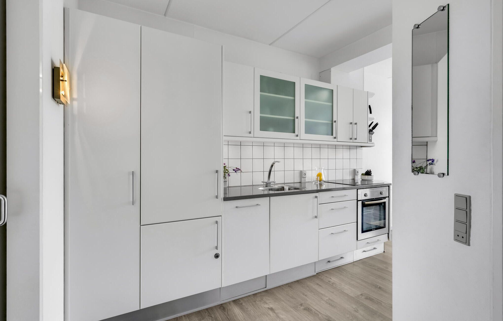 Een moderne keuken met witte kasten, een roestvrijstalen spoelbak en een inbouwoven.