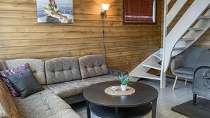 A cozy living room with a sofa, a round coffee table, a staircase, and a wall-mounted lamp. - Beautiful home in Offersøy with kitchen (Offersøy)