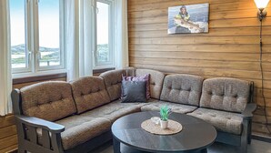 A corner seating area with a sofa and a round coffee table, a painting on the wall, and a view through the window. - Beautiful home in Offersøy with kitchen (Offersøy)