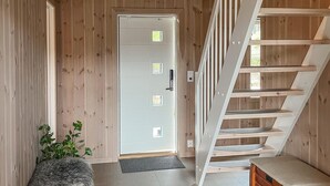 A wooden interior with a white door, a staircase, and a small wooden chest. - Lovely home in Treungen (Treungen)