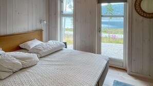 A bedroom with a bed, a wooden headboard, a window, and a view of a lake. - Lovely home in Treungen (Treungen)