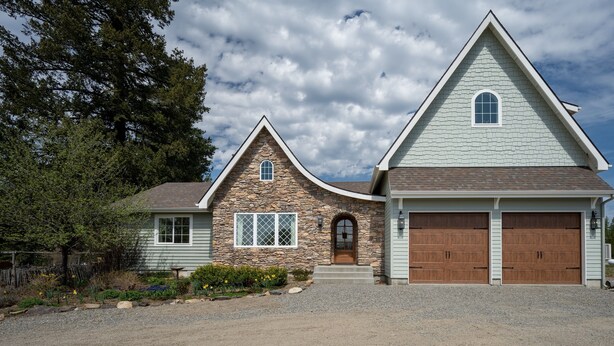 A two-story house with a stone facade, a stone chimney, and a large garage.