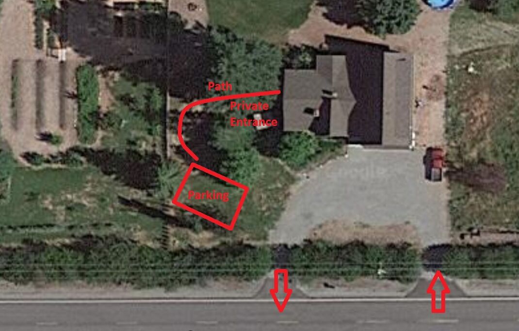 Satellitenansicht eines Wohngebiets mit privatem Eingang, Parkplätzen und einem Weg.
