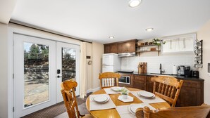 A modern kitchen with wooden cabinets, a white refrigerator, and a dining area with a round table and chairs.