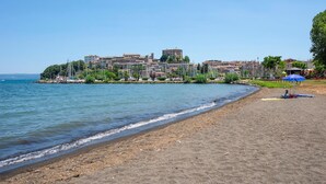 Une plage bordée d’une rangée de bâtiments en arrière-plan, un rivage sablonneux et un ciel bleu clair.