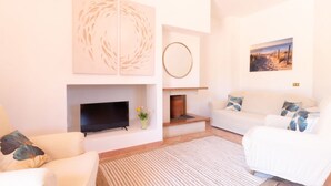 Uma sala de estar moderna com televisão de tela plana, lareira e sofá branco.