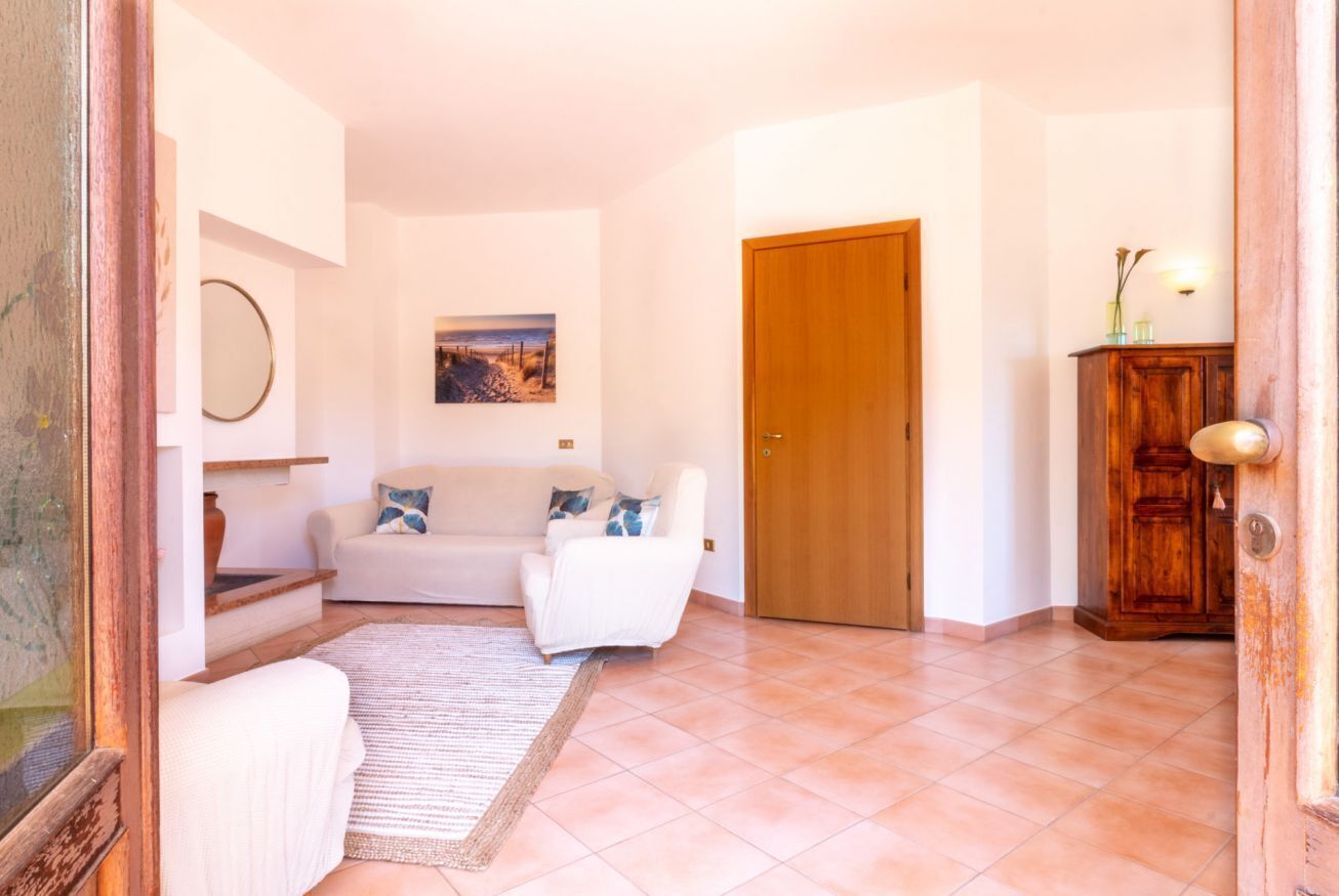 Una sala de estar con un sofá blanco, un aparador de madera y una puerta.