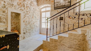 A stone staircase with a metal railing, a framed picture on the wall, and a door leading to another room.