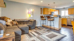 A modern living room with a sectional sofa, a coffee table, and a kitchen area with wooden cabinets and a stainless steel dishwasher. - 12 Mi to Denver: Golden Vacation Rental! (Golden)