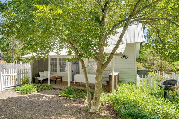 A white wooden house with a porch, a covered seating area, and a barbecue grill.