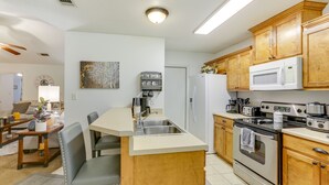 Una cocina con armarios de madera, microondas integrado, estufa y pileta.