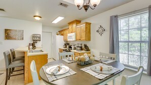 Una cocina moderna con armarios de madera, un microondas y un comedor con una mesa redonda para cuatro.