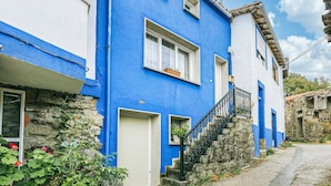 A two-story building with a blue facade, white trim, and a stone staircase leading to the entrance.