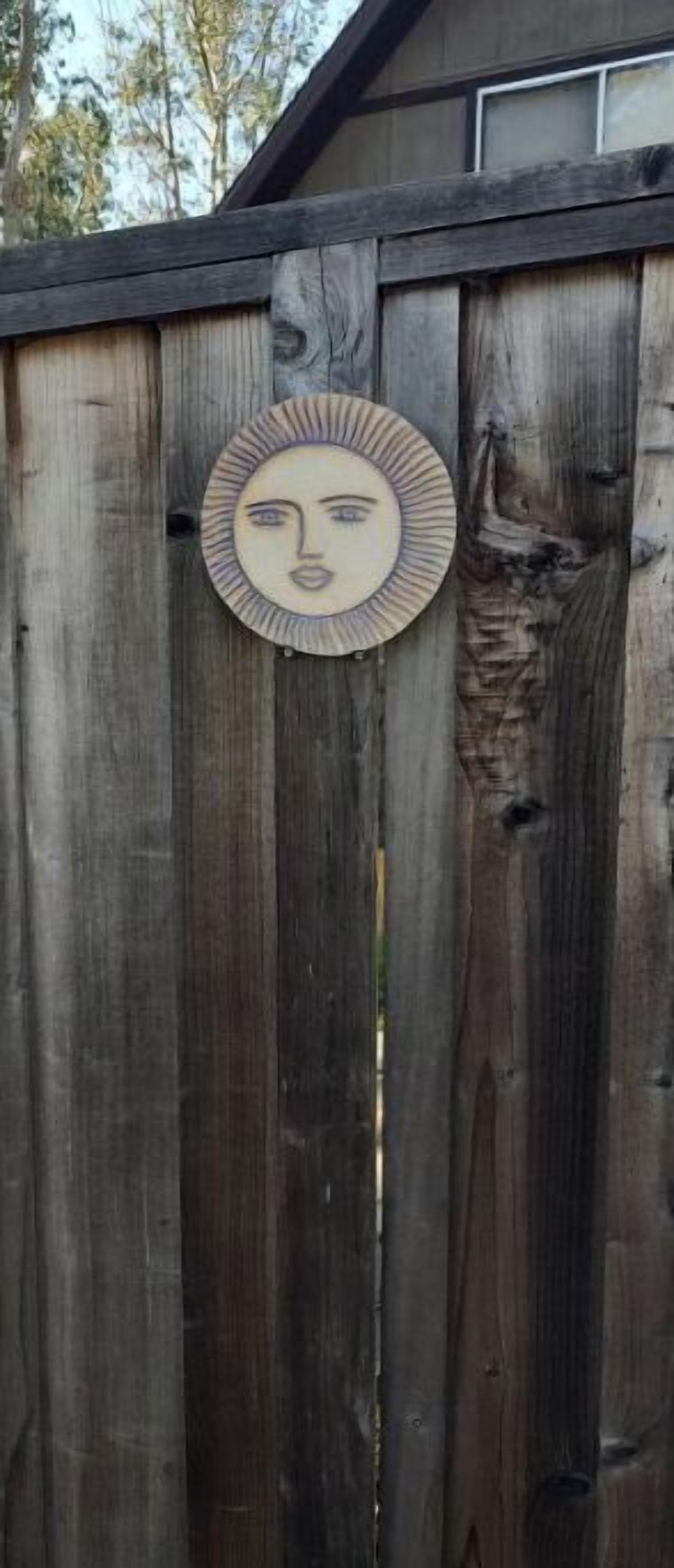 A wooden fence with a circular decorative item hanging on it.