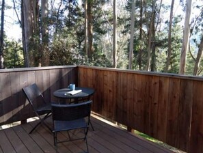 A wooden deck with a table and two chairs, surrounded by a wooden fence and tall trees. - Haven in the trees, minutes from hiking trails (Mill Valley)