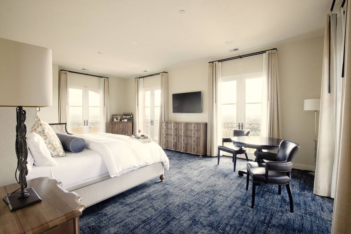 A hotel room with a bed, a desk, a chair, a television, and a wardrobe.