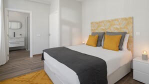 Een moderne slaapkamer met een groot bed, witte muren en een houten vloer.