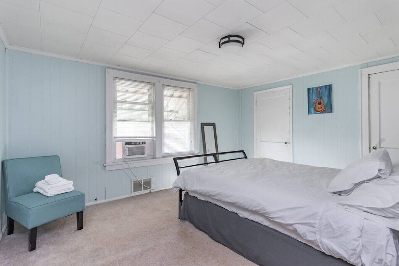 Un dormitorio con cama, una silla y ventana con persianas.