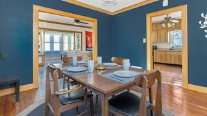 A dining area with a wooden table and chairs, a ceiling fan, and a view into the kitchen. - Home of the Braves - Bradley Campus Suite (West Peoria)