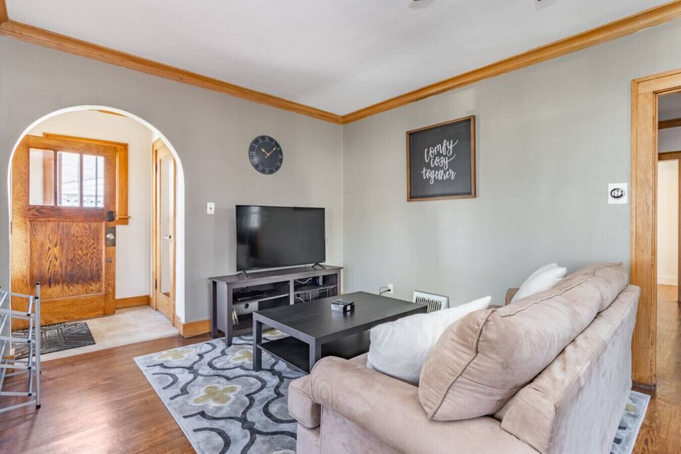 Un salón con sofá, televisión y un reloj en la pared.