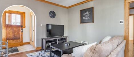Un salón con sofá, televisión y un reloj en la pared.