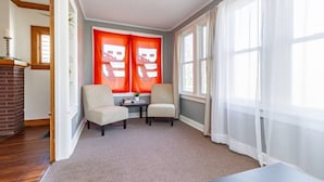 A room with two armchairs, a small table, and a fireplace. - Home of the Braves - Bradley Campus Suite (West Peoria)