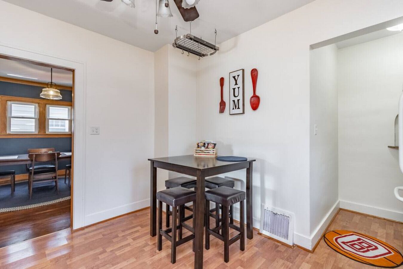 A dining area with a dark wooden table and four chairs, a small stack of books, and a red spoon on the wall.