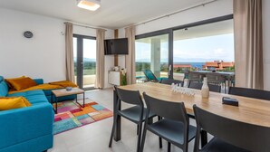 Ein modernes Wohnzimmer mit einer Couch, einem Couchtisch und einem Essbereich mit Stühlen und einem Tisch.
