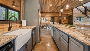 Eine moderne Küche mit Granitarbeitsplatten, Edelstahlgeräten und Holzbalken an der Decke.
