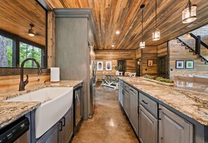 Eine moderne Küche mit Granitarbeitsplatten, Edelstahlgeräten und Holzbalken an der Decke.