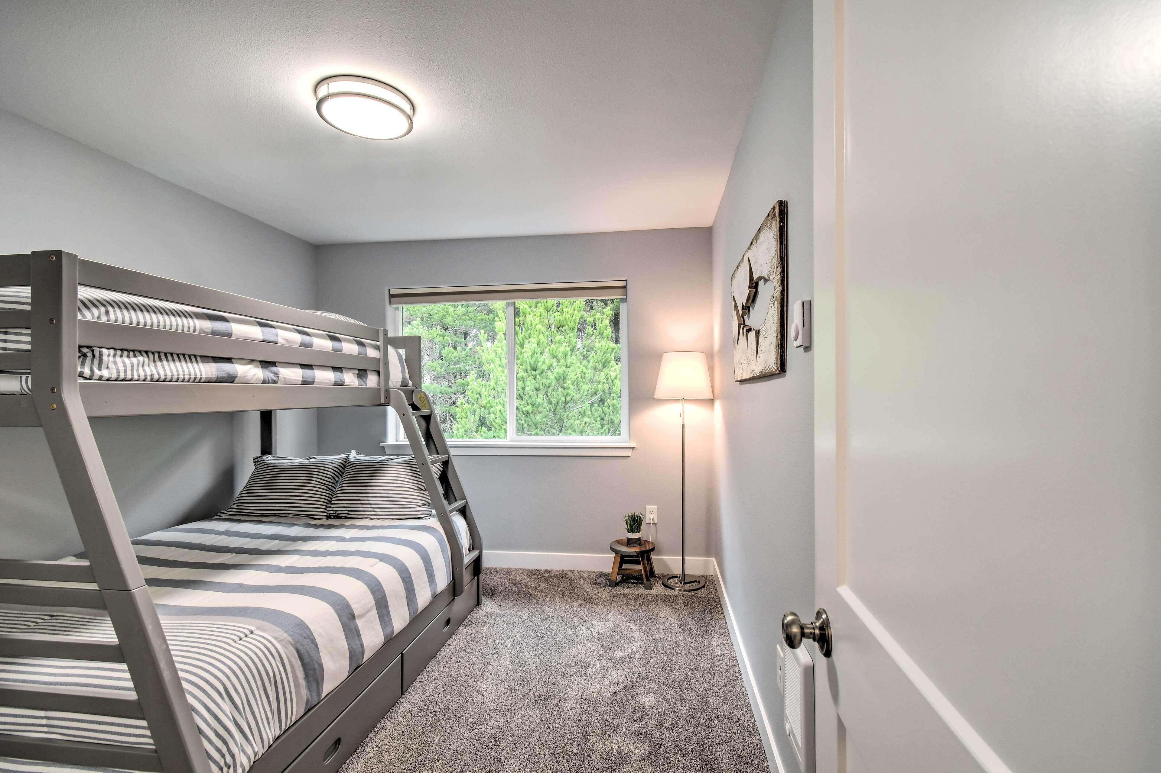 A bunk bed room with a window, a lamp, and a small table.