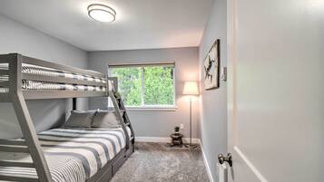 A bunk bed room with a window, a lamp, and a small table.
