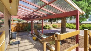 A covered patio area with a wooden bench, a hammock, and a basketball hoop.