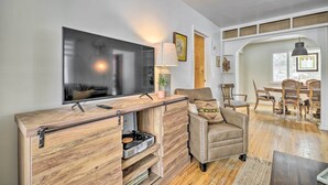 A modern living room with a flat-screen TV, wooden entertainment unit, leather armchair, and a dining area with wooden chairs and a table. - 1 Mi to Hot Springs! Central Thermopolis Home (Thermopolis)
