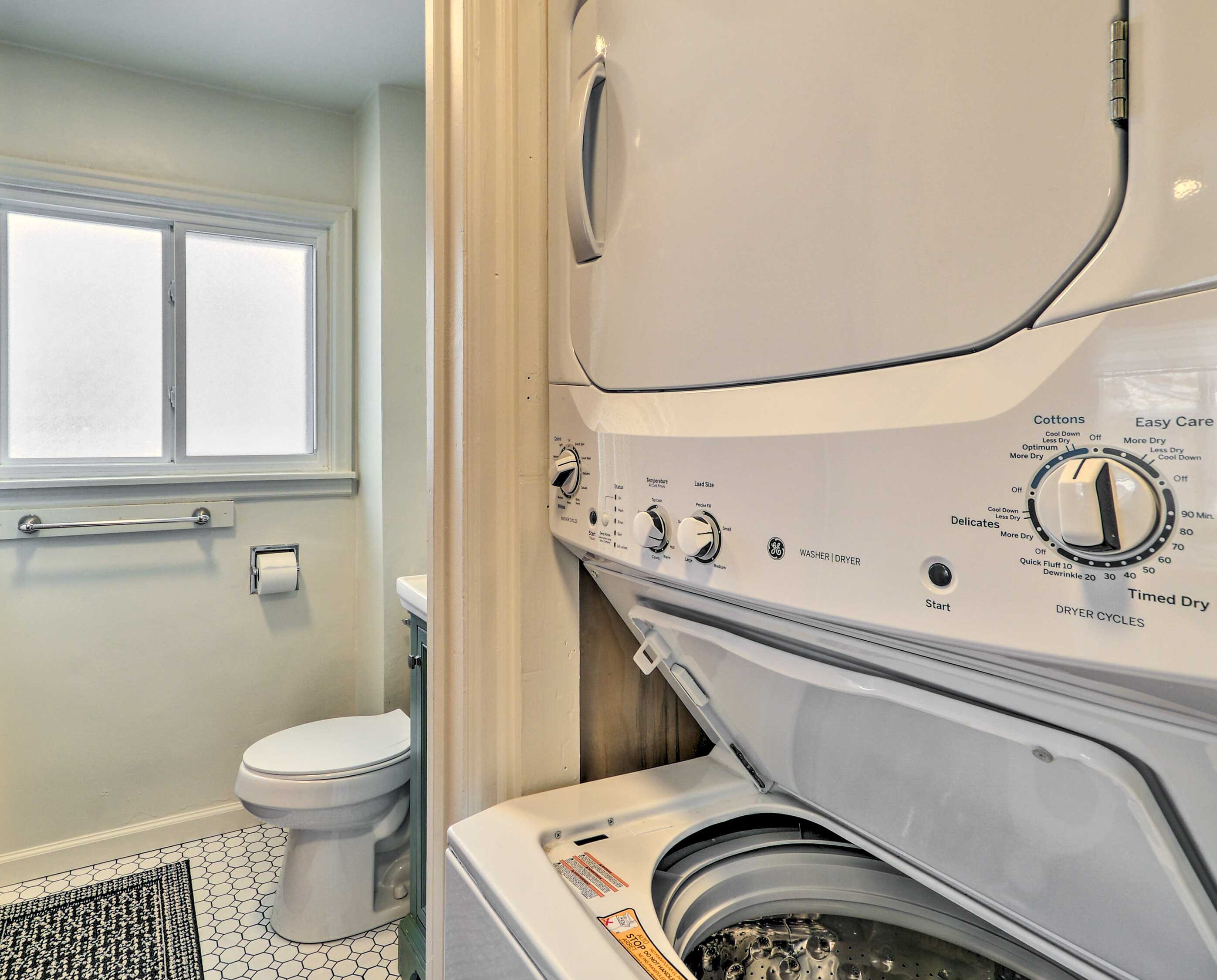 A compact bathroom with a toilet, a washing machine, and a dryer.