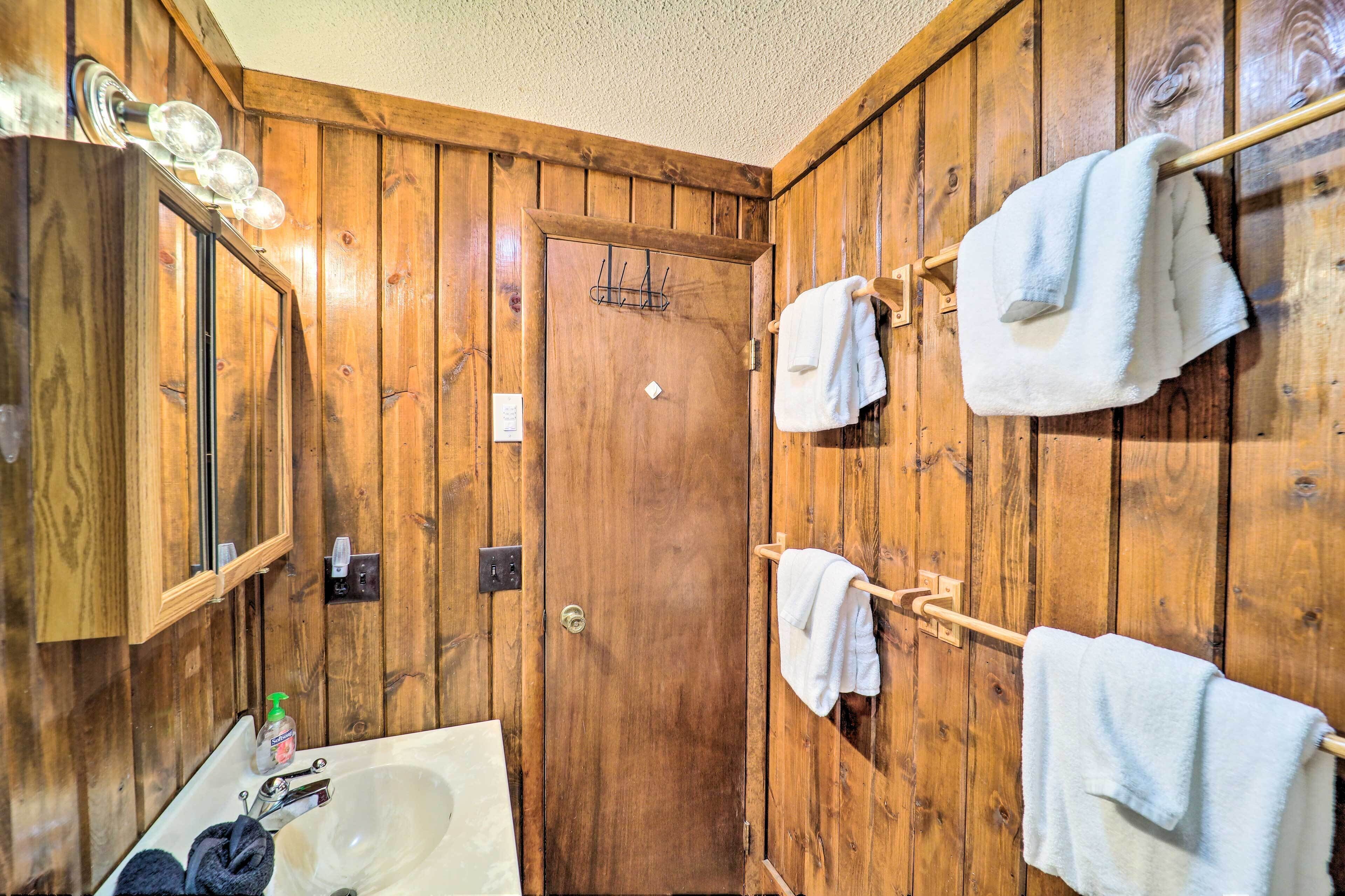 A wooden-paneled bathroom with a sink, mirror, and towel rack.