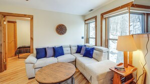 A cozy living room with a sectional sofa, a round coffee table, and large windows offering a view of the outdoors. - Beech Mountain Cabin w/ Deck: Half-mi to Skiing (Banner Elk)
