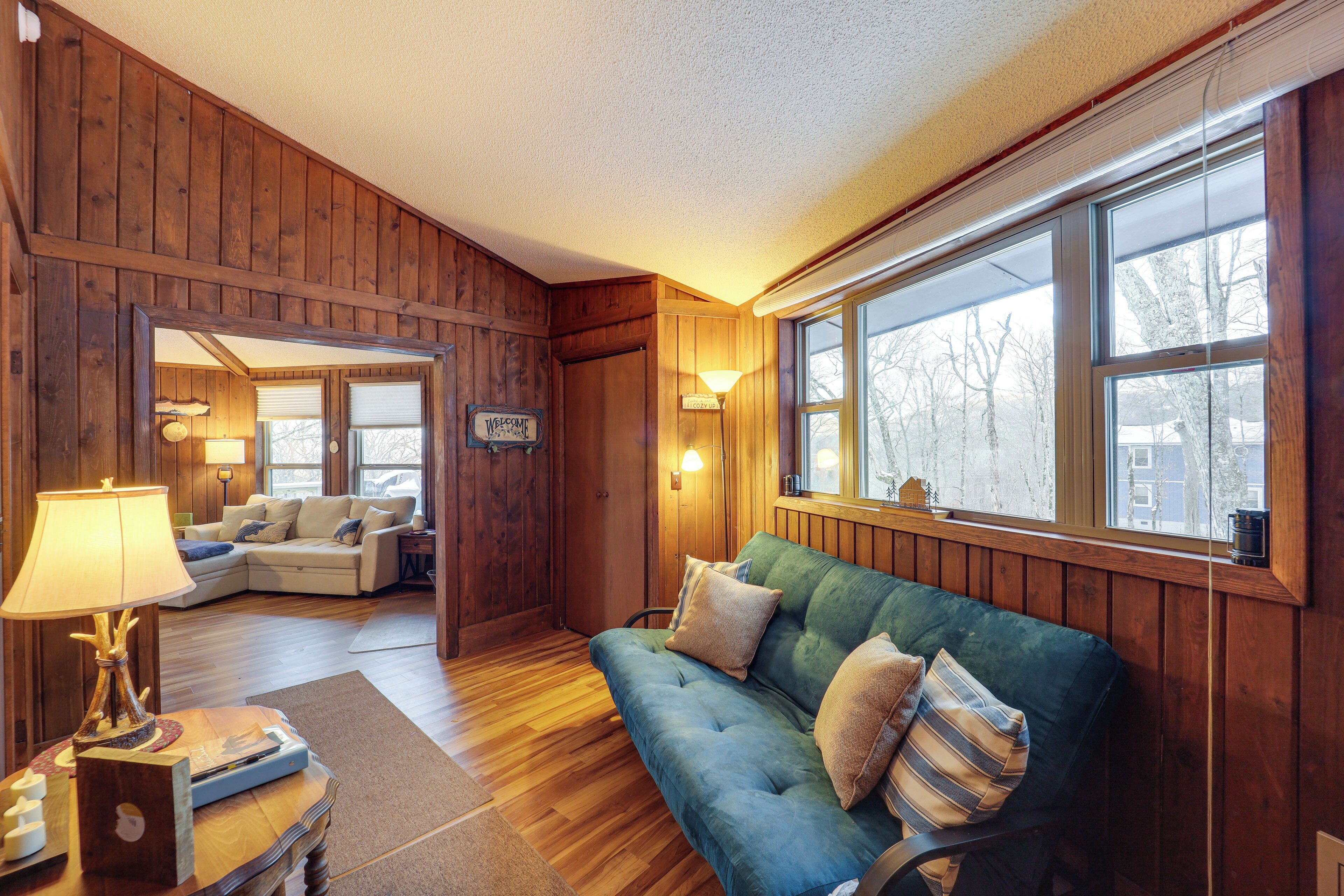 Una habitación acogedora con paredes de madera, un sofá verde, una mesita de madera y una lámpara.