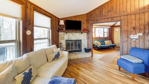 A cozy cabin interior with a stone fireplace, wooden walls, a sofa, and a blue armchair. - Beech Mountain Cabin w/ Deck: Half-mi to Skiing (Banner Elk)