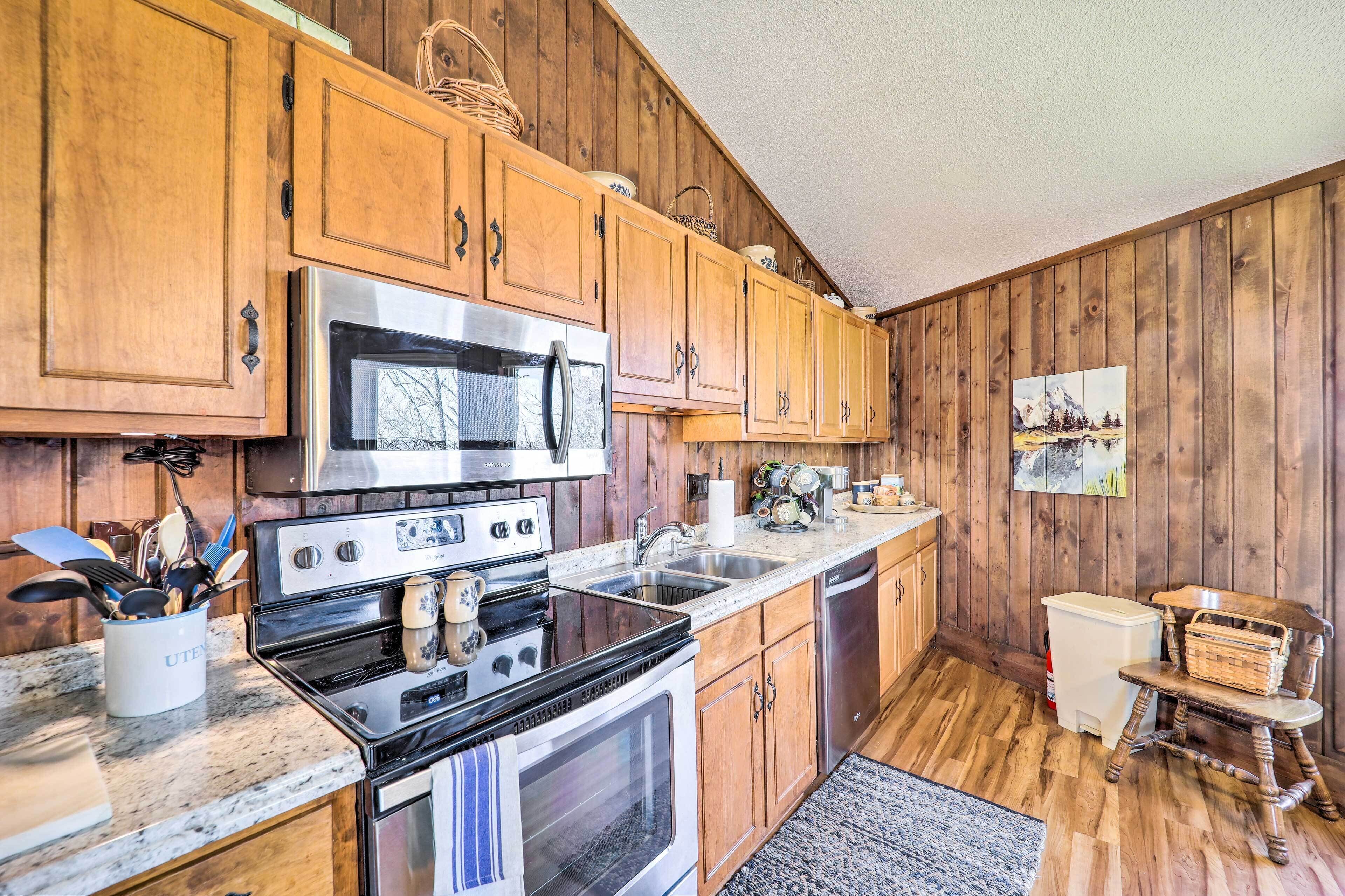 A kitchen with wooden cabinets, stainless steel appliances, granite countertops, and a wooden floor.
